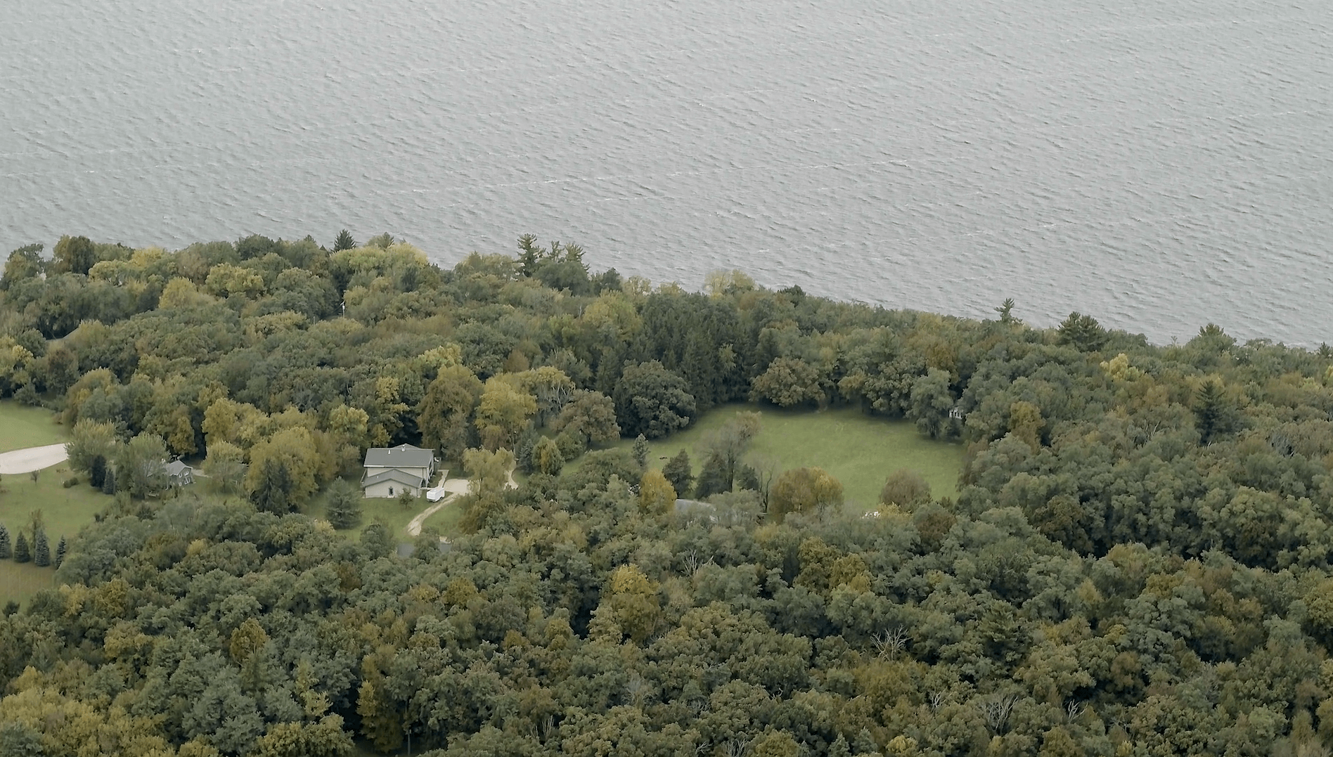 An aerial view of the Tichora Conservancy with a house surrounded by trees and on the shore of a lake.