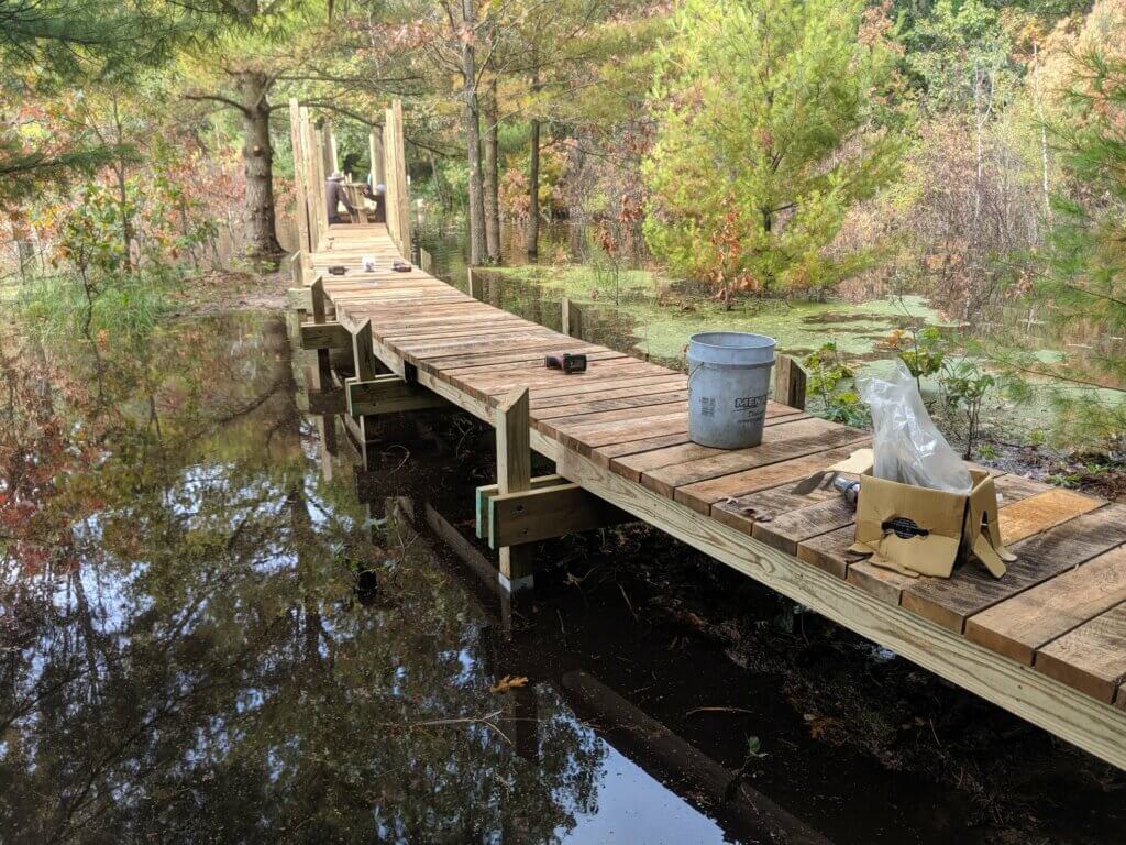 A boardwalk being built over a water filled marsh.