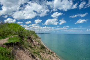 A bluff in Ozaukee County, Wisconsin with a green and sandy bank on the left and the lake on the right.