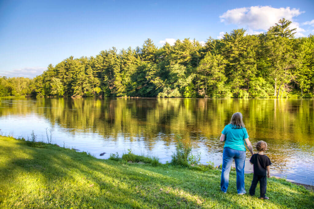 Parent and child along a river, near a forest, in Wisconsin. Funding restrictions and a shorter renewal of the Knowles-Nelson Stewardship Program will make it more difficult to protect such landscapes across Wisconsin.