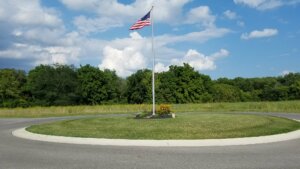Knowles-Nelson Stewardship Program, American flag flapping in the wind over a grassy cul-de-sac with trees in the background