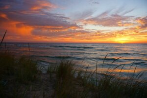 Knowles-Nelson Stewardship Program, sunset with bright orange sky over Lake Michigan with sandy grassy beach