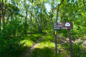 Knowles-Nelson Stewardship Program - a brown sign that reads Ice Age National Scenic Trail amidst a backdrop of a green wooded area