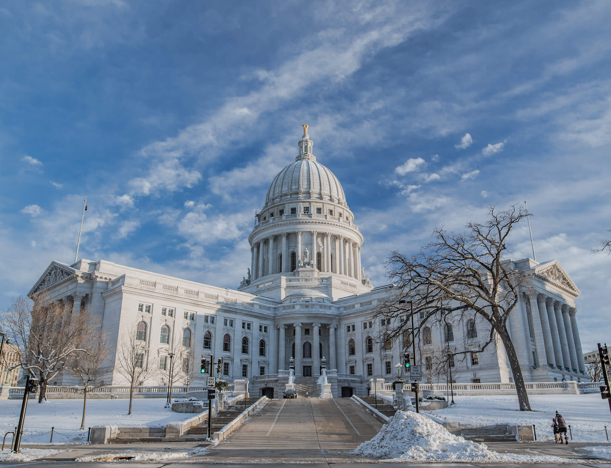 Wisconsin state capitol building in winter with snow covered grass and the looming white building in the back,
