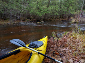 A kayak sits on the bank of the Little Wolf River.