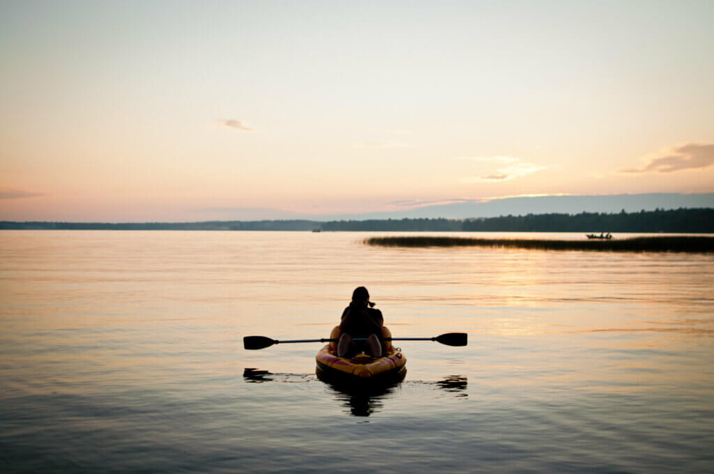 Silhouette of a kayak on a lake at sunset.