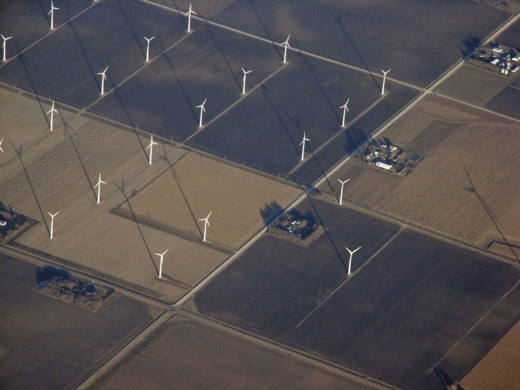 Aerial view of windwills spaced out evenly across farmland.