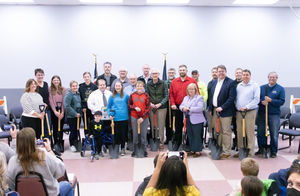 A group of people standing indoors holding shovels.