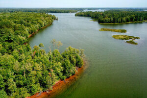 An aerial view of a large river flowage surrounded by green trees and dotted with small islands.