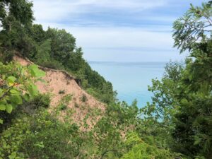 Steep, sandy bluff overlooking Lake Michigan, covered in green vegetation.