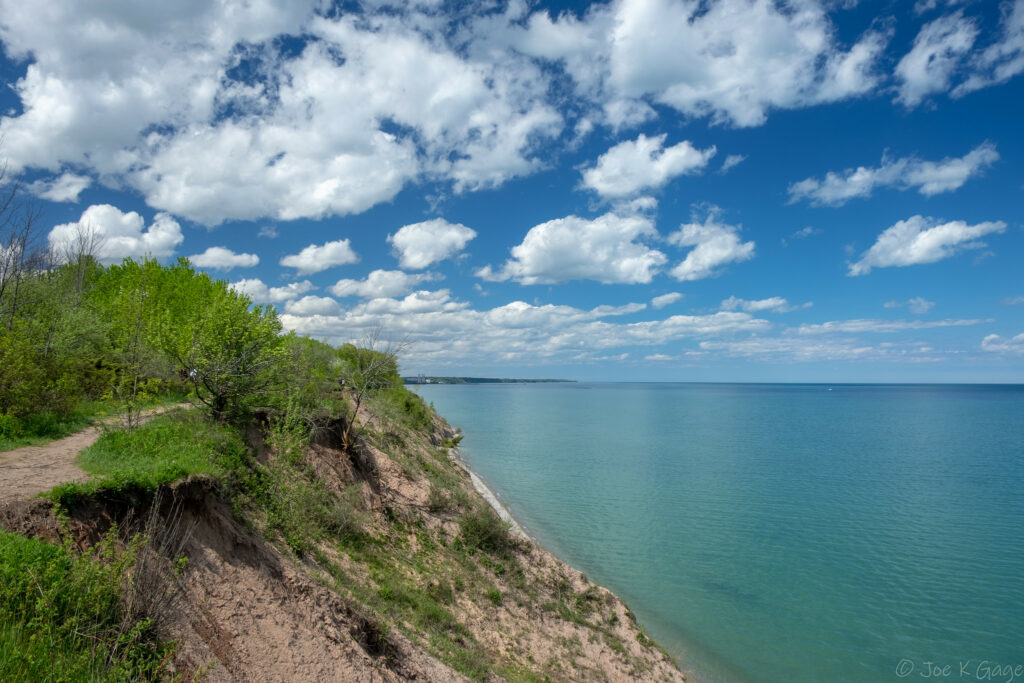 Steep, sandy bluff overlooking Lake Michigan, covered in green vegetation.