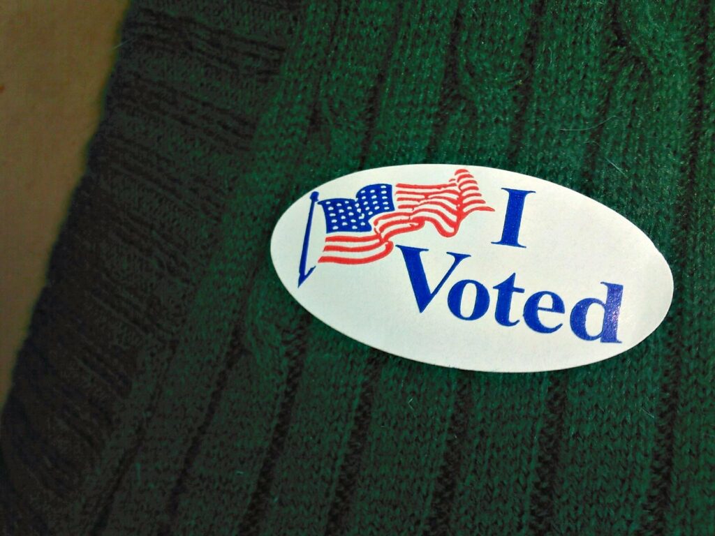 Close up of an 'I Voted' sticker on a a green sweater.