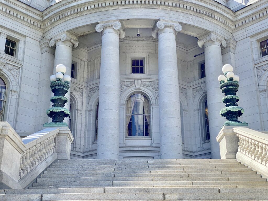 White stone facade of the Wisconsin Capitol building featuring decorative carvings, pillars, and arched windows.