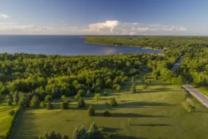 Aerial view of a park with green trees perched on a bluff near the shoreline.