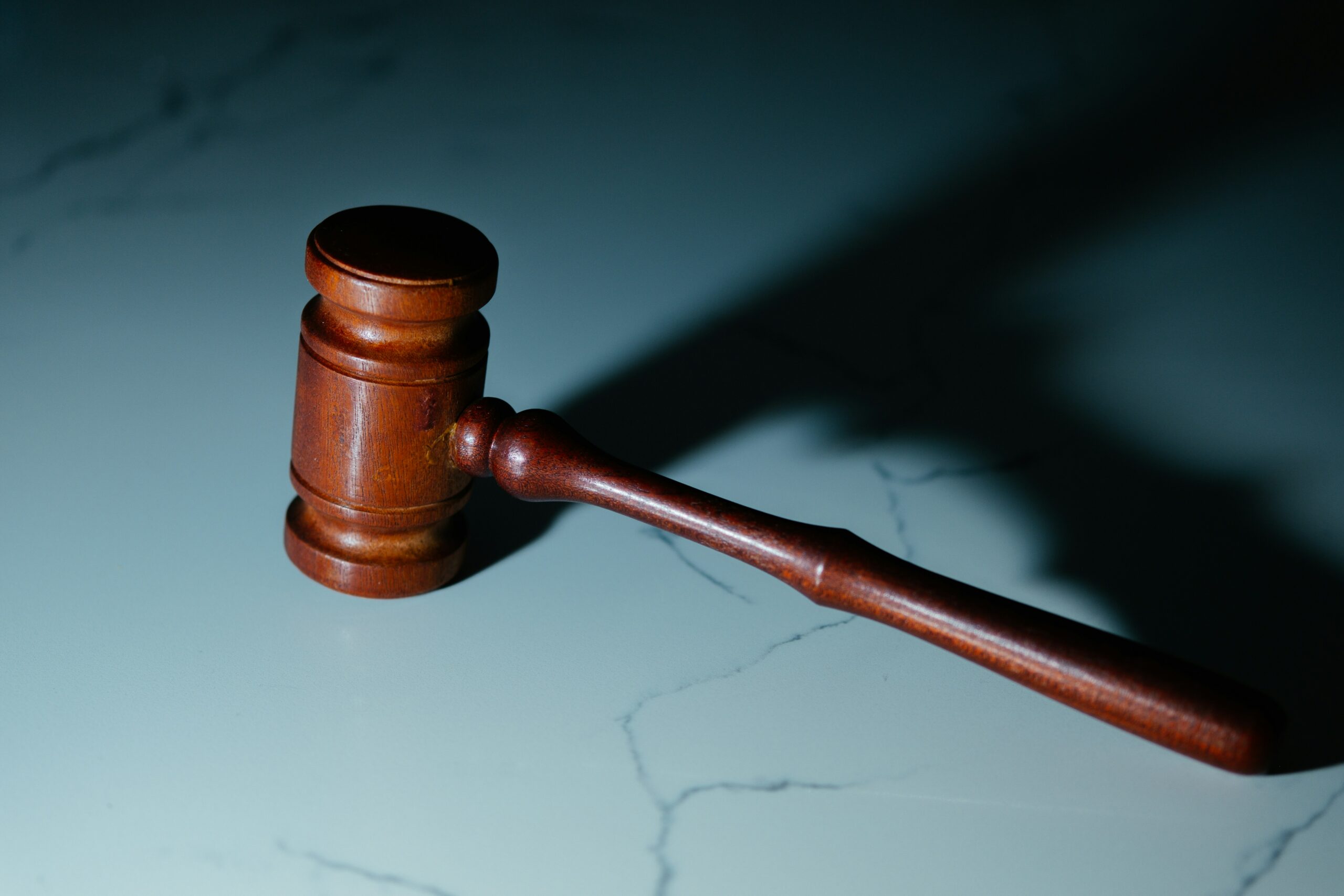 Wooden judge's gavel sitting on top of a white marble table.