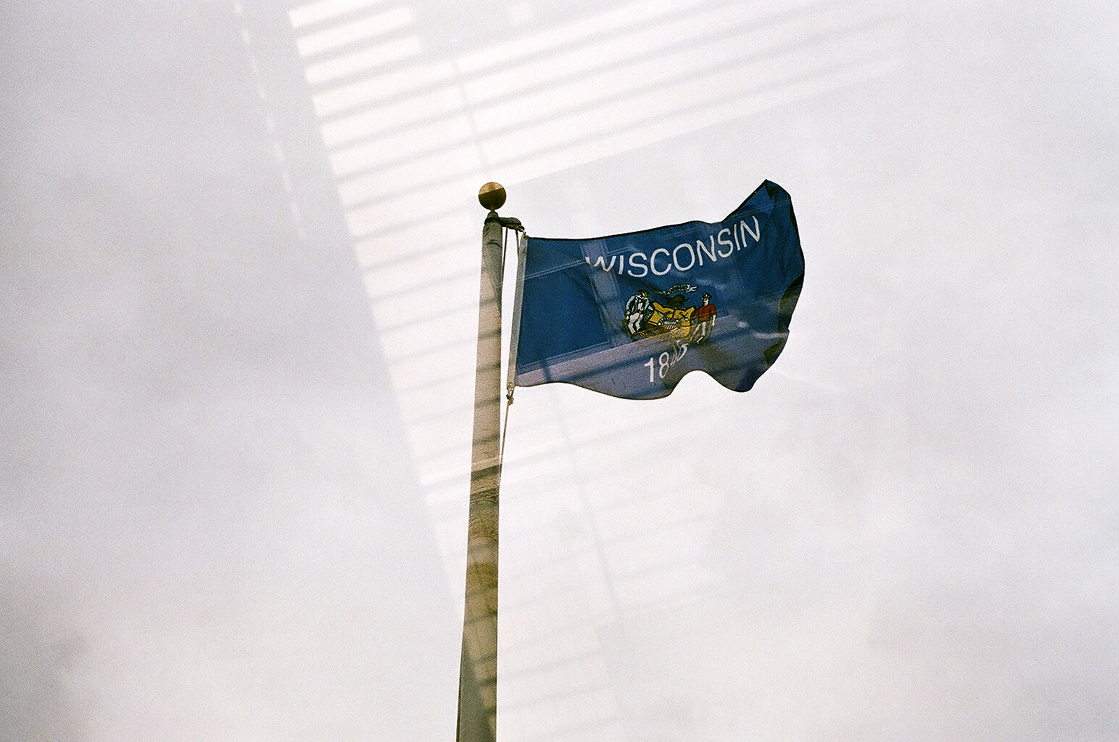 Looking up towards the Wisconsin state flag waving on a flag pole.