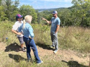 A man talking to a man and woman. They are standing on a trail.