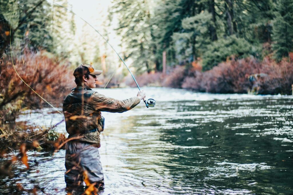 Man fishing in a river during the daytime.