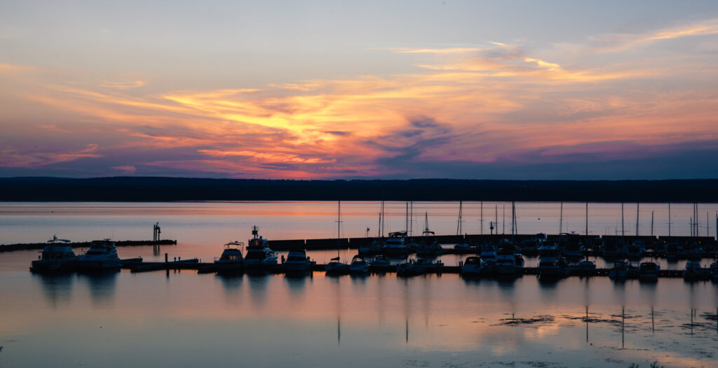 A harbor with several sailboats at sunset.