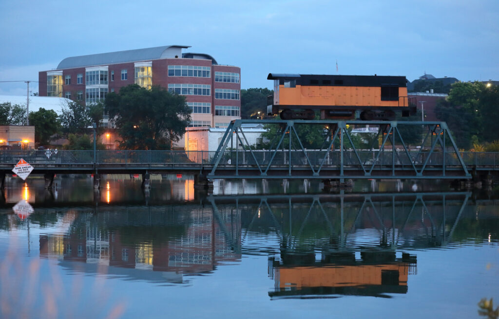 A railroad bridge crosses a body of water in a small city.