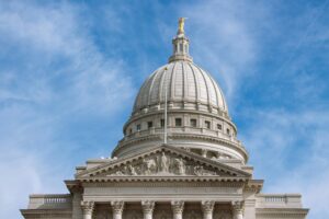 Exterior of Wisconsin Capitol Building rotunda against a blue sky with wispy clouds.