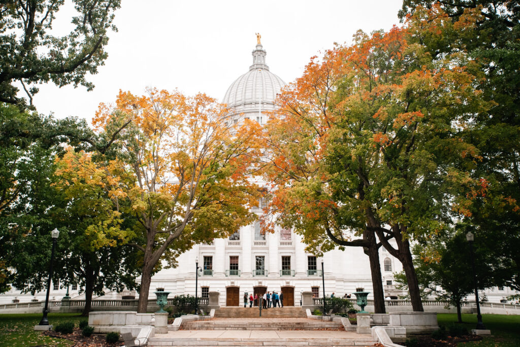 The Wisconsin Capitol Building peeks out from behind trees beginning to show fall color.