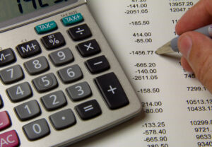 Close-up shot of a calculator on top of a financial statement and the tip of a pen.,