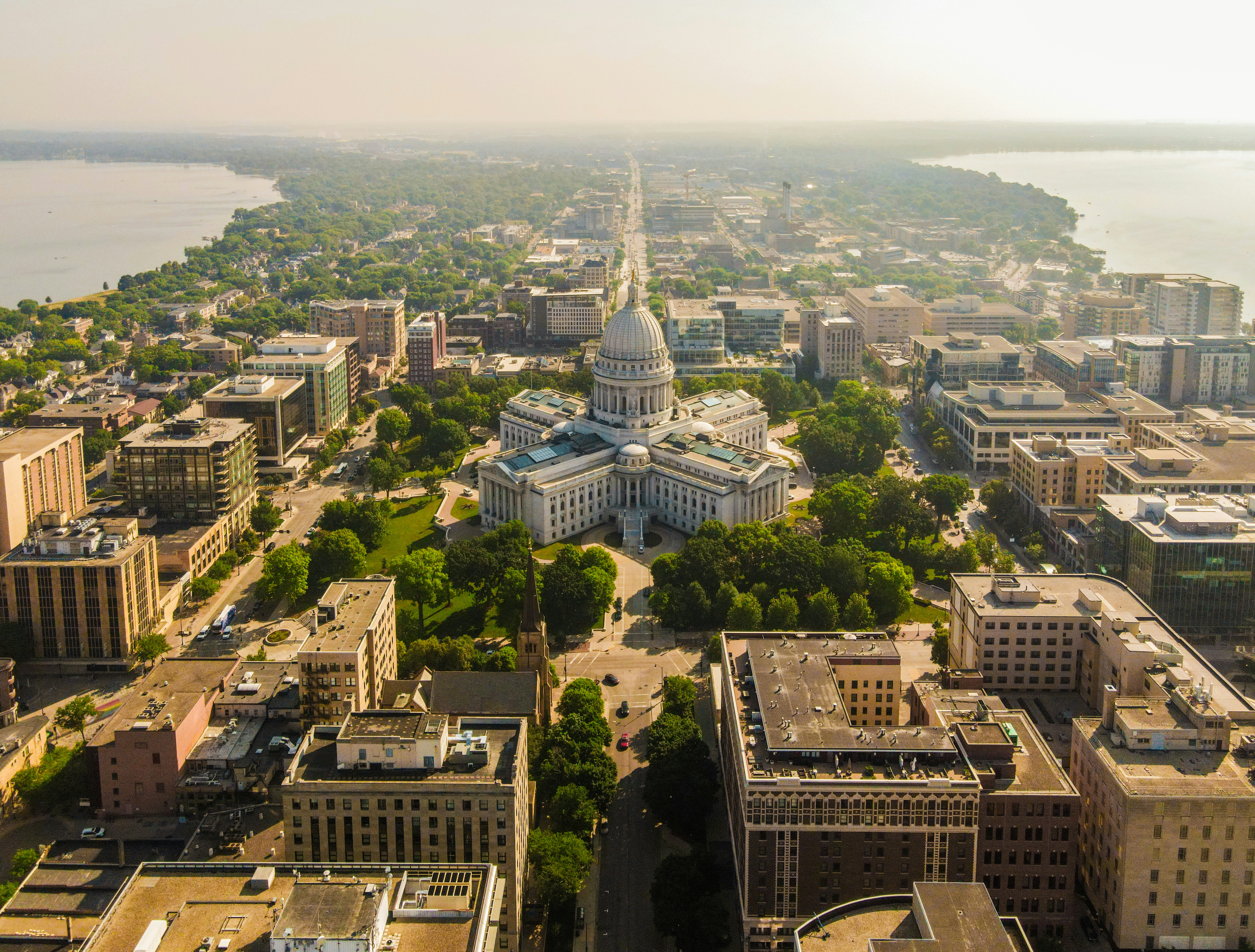 Aerial view of downtown Madison, with the capitol building in the center, and bodies of water lining either side of the city.