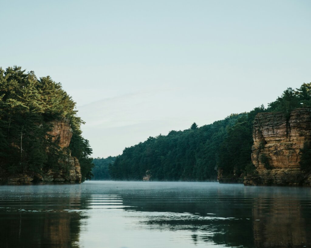 Green trees and bluffs line both sides of a river during daytime.